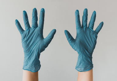 Photographie d'une paire de main en l'air portant des gants en latex