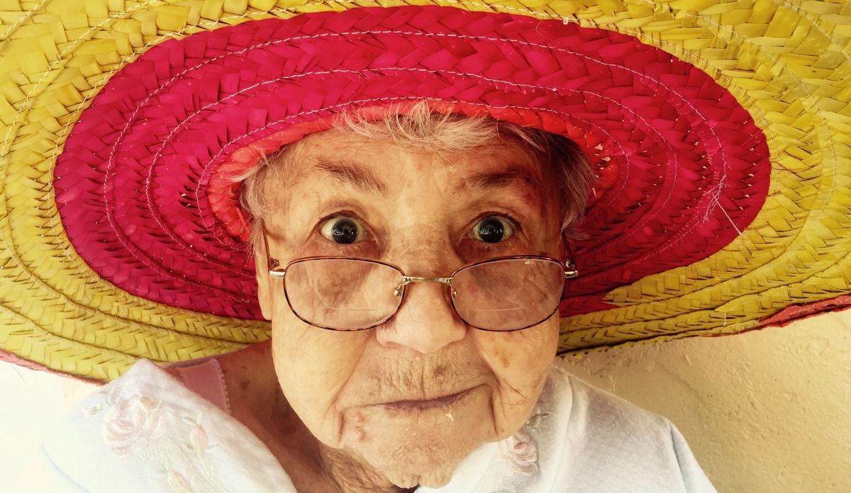 Photographie d'une vieille dame à lunettes avec un sombrero rouge et jaune