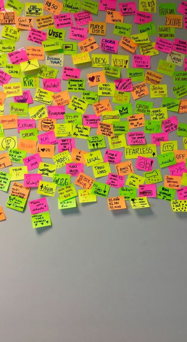 Photographie d'un mur de Post It Jaunes, verts et roses