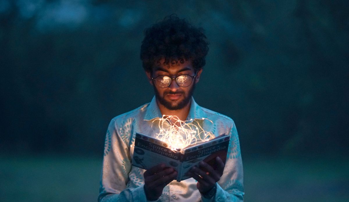 Photographie d'un homme lisant un livre lumineux dans la pénombre