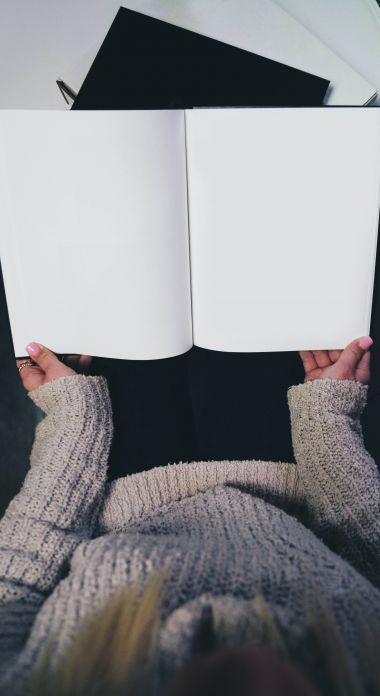 Photographie d'une femme tenant un livre blanc ouvert