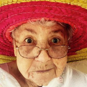 Photographie d'une vieille dame à lunettes avec un sombrero rouge et jaune