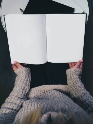 Photographie d'une femme tenant un livre blanc ouvert