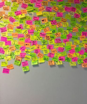 Photographie d'un mur de Post It Jaunes, verts et roses